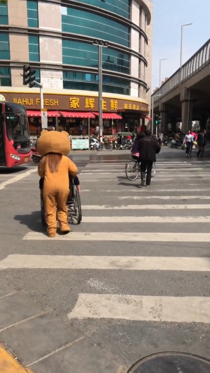 小熊把要过马路的阿姨推过斑马线