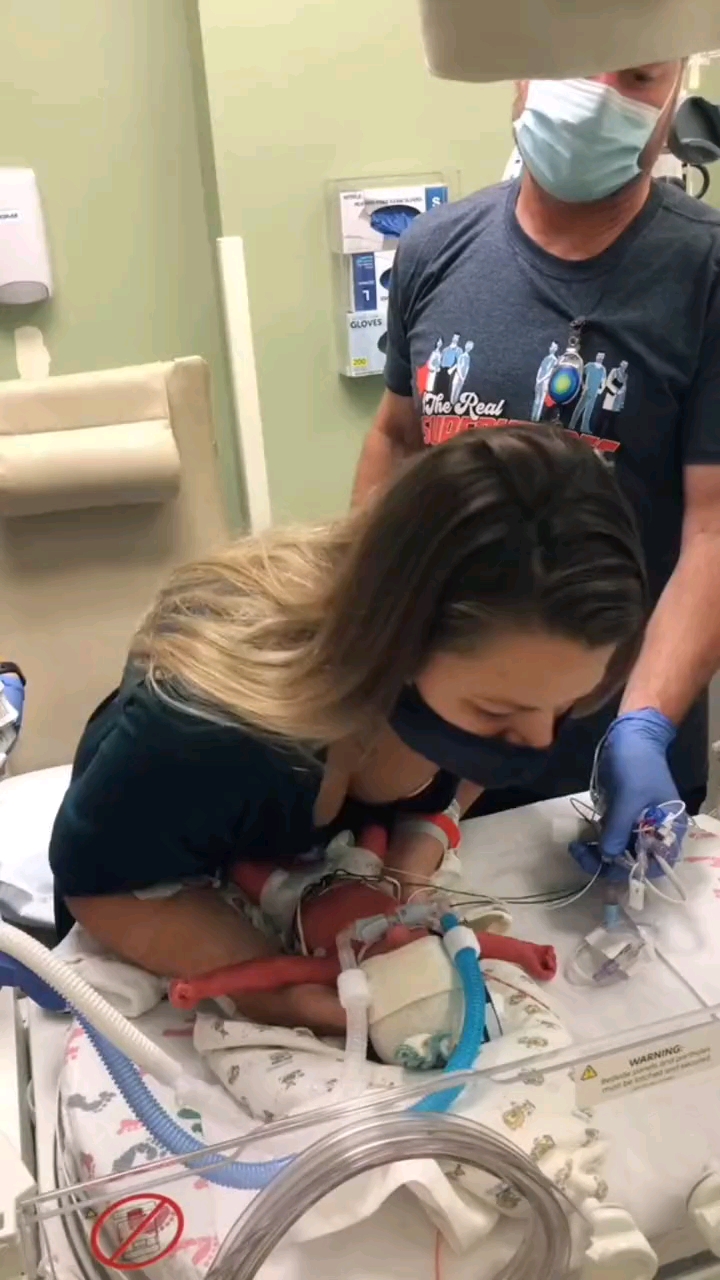 母亲第一次抱起插满管子的早产儿