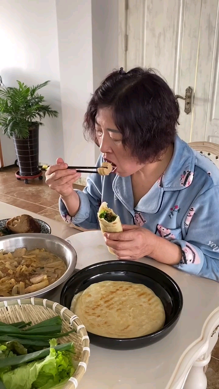 东北大姐到饭点了,白菜粉条炖肉,再烙几张油饼,大姐说:这大饼卷菜,老