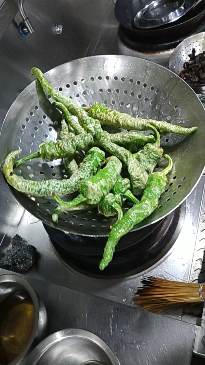 虎皮辣椒炸好后迅速放入凉水中冲凉.辣椒不会变色.
