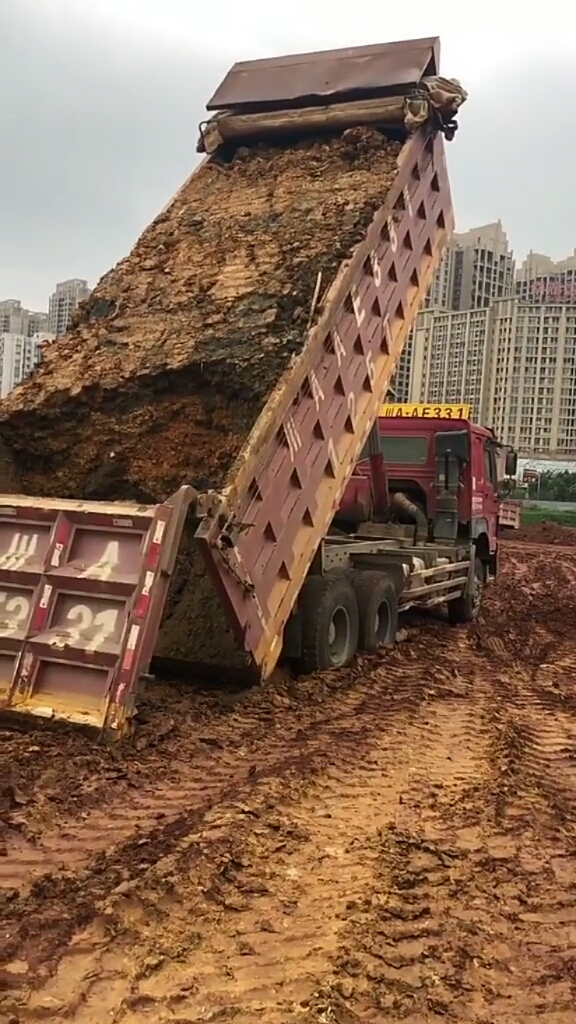 渣土车装的土倒不出来了,装的时候被挖掘机压得太紧了,真是多一趟的